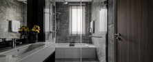 Luxurious dark marble master bathroom featuring long vanity counter, glass shower enclosure, and soaking tub setup.