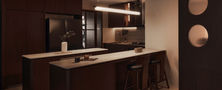 Spacious Mid-century Modern kitchen featuring dark timber cabinets double island setup and circular cutout partition by Intheory Design Singapore.