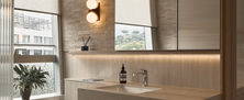 Modern bright bathroom vanity featuring floating stone sink mirror medicine cabinet and warm wall sconce lighting.