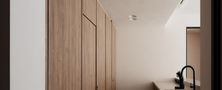 Architectural view through a soft arch doorway revealing full-height wood panelled storage cabinets and herringbone wood floor in a Scandinavian home.