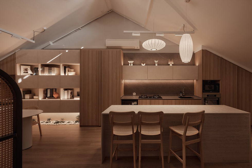 A wide-angle view of an open-plan attic studio featuring a stone kitchen island, light wood cabinetry, and a communal workspace under a vaulted ceiling.