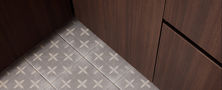 Fine carpentry and flooring detail showcasing dark timber wardrobe base and patterned geometric floor tiles.