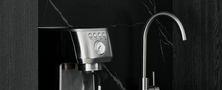 Dedicated home coffee bar counter featuring dark marble backsplash, espresso machine, and sleek tapware.