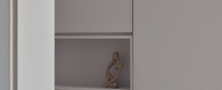 Seamless white built-in cabinet design featuring push-to-open doors and a decorative display shelf.