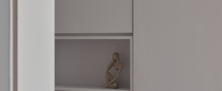 Seamless white built-in cabinet design featuring push-to-open doors and a decorative display shelf.