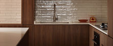 Eclectic kitchen corner with rich dark wood cabinets, black cooktop, sleek faucet, and decorative patterned backsplash tiles.