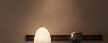 Warmly lit Dark Japandi sideboard counter with a textured paper table lamp and dark wall backdrop.