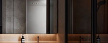 High-contrast dark bathroom vanity featuring floating counter, integrated basin, backlit rectangular mirror, and glass shower partition.