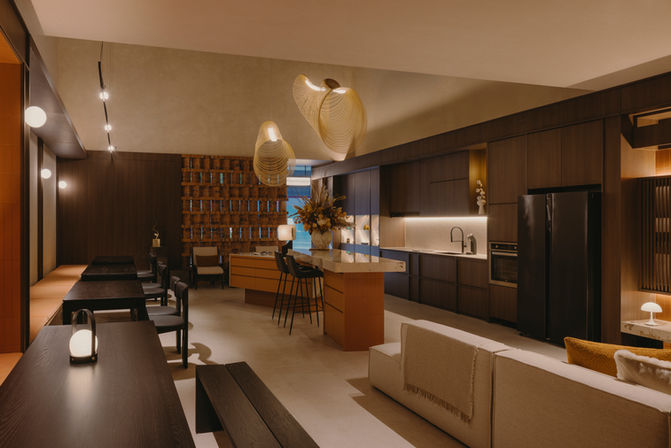 A panoramic view of a luxury showroom living space with dark wood wall cladding, minimalist furniture, and cove lighting.