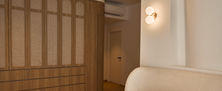 Tropical Modern master bedroom layout featuring custom wood wardrobe with arched glass panels cream padded headboard and double globe sconce.