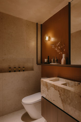 Luxury bathroom design featuring a marble floating vanity, circular wall sconce, and warm earthy-toned walls.