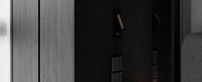 Atmospheric bedside corner featuring dark wood panelling, minimalist nightstand, and glowing orb light.