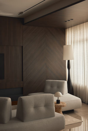 Modern light-colored armchairs in a room with dark wood walls and a floor lamp.