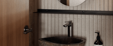 Modern Ryokan washroom vanity featuring a natural stone vessel sink, pill-shaped mirror, and fluted tile accent wall.