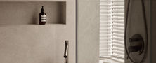 Relaxing Light Resort Japandi bathroom tub nook with microcement walls recessed wall niche display and dark shower fixtures.