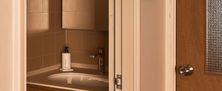 Frame-within-a-frame view looking into a cozy washroom vanity with a backlit mirror and warm wood panelling.