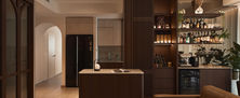 Tropical Modern open-plan interior featuring integrated dry bar with wine fridge island counter and warm ambient illumination.