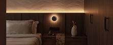 Dark Japandi master bedroom featuring custom dark wood headboard wall warm LED strip light and circular sconce lamp.