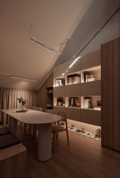 Recessed wall shelving in a modern office, featuring warm integrated lighting, curated books, and a view toward a minimalist workspace.