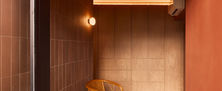 Earthy balcony seating area with terracotta walls, ambient cove lighting, and a vintage woven rattan armchair.