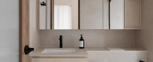 Scandinavian bathroom vanity design with a beige floating counter, medicine mirror cabinet, integrated sink, and modern double globe wall sconce.