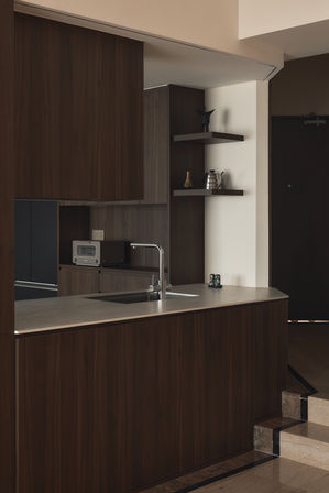 A modern kitchen with dark wood cabinets and a view through to a dining area.