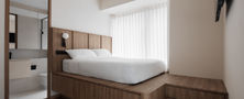 Minimalist Scandinavian master bedroom layout featuring a custom wood platform bed with storage steps and direct view into an en-suite bathroom.