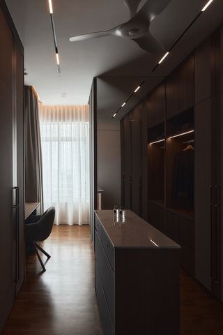 A narrow dressing room with tall dark wood wardrobes and a central island.