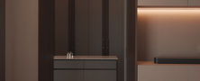 Minimalist dressing nook featuring integrated storage, soft backlit recess lighting, and a neutral ottoman stool.