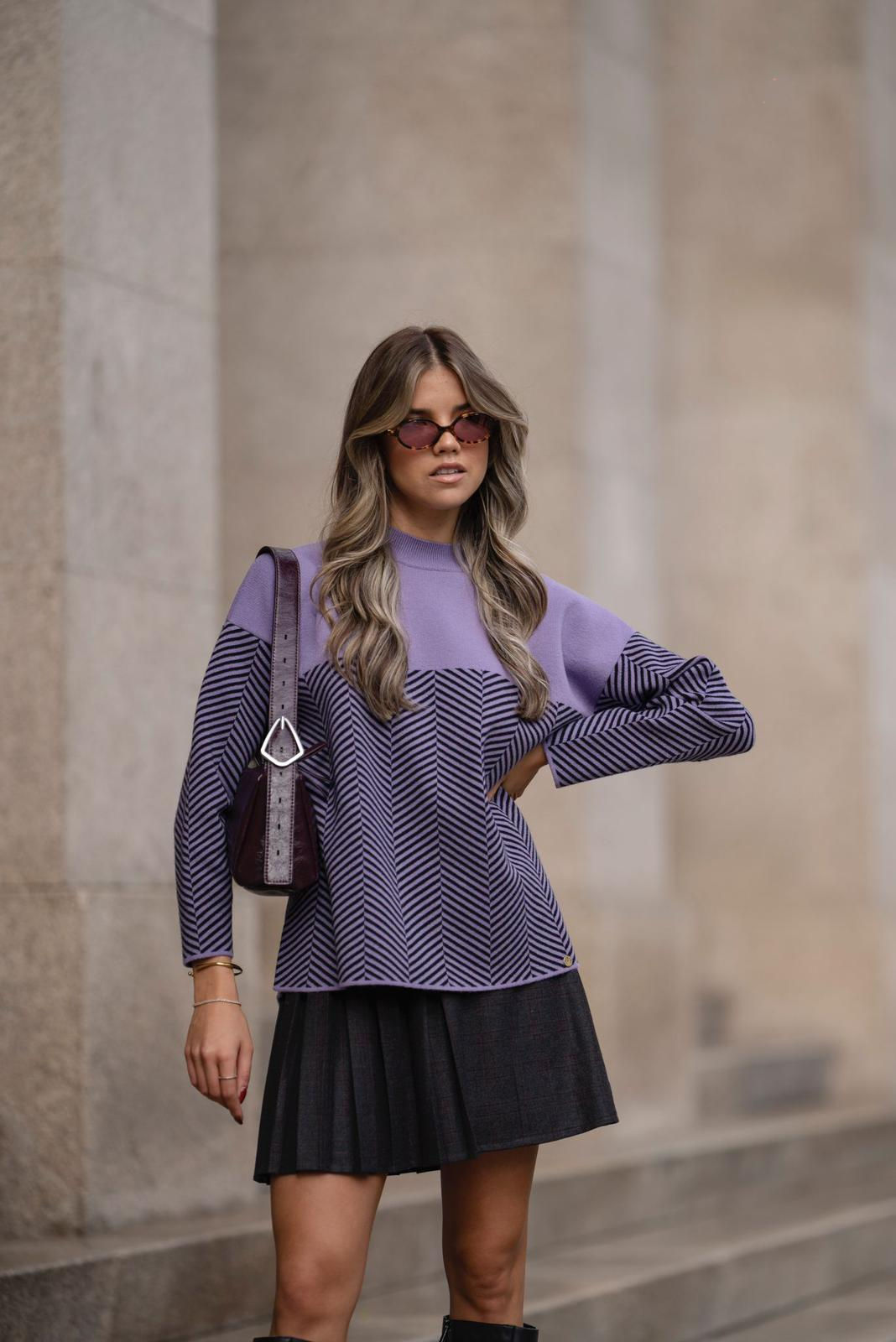 Suéter listrado em lilás e preto no modelo, trazendo um toque de cor e estilo ao visual.