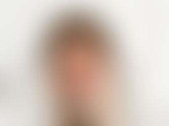 Woman wrapped in white blanket looks thoughtful and slightly concerned. Plain white background adds to the pensive mood.
