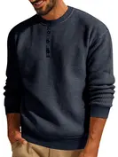 Man wearing a navy blue Henley shirt, smiling, with tan pants on white background.