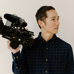 Owner of Jeremy Ito Story Design holding camera and looking to the right