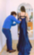 Tailor at Kleermaker Williams LLC pinning a client’s blue evening gown with a flowing train during a professional fitting for a custom alteration and perfect fit.