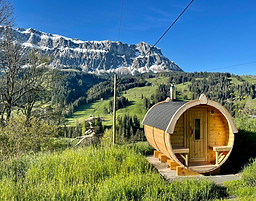 Sauna in den Bergen. Tolles Saunafass mit Panoramafenster mit Blick zum Hogant