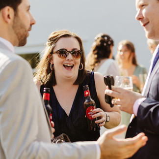 wedding guest laughs holding two beers