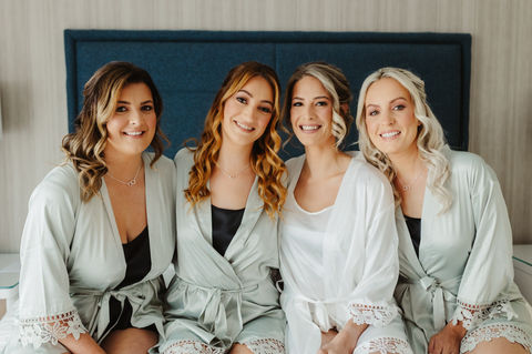 bride and her 3 bridesmaids posing on the bed pre wedding at Southampton Harbour hotel