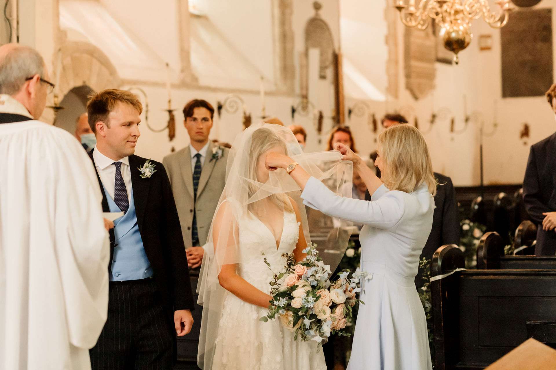 mother of the bride lifts bride's veil from her face