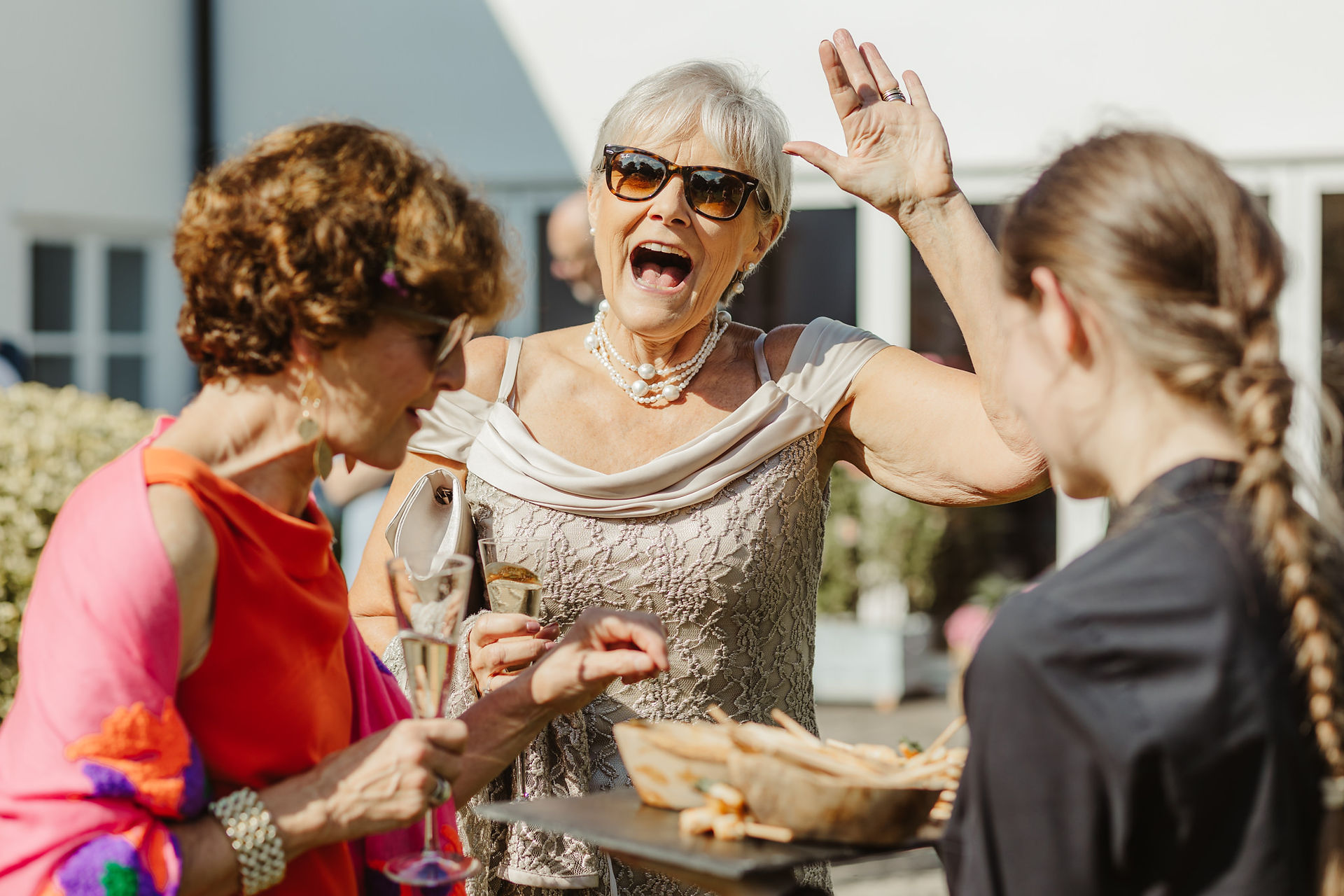 female wedding guests waves at the camera smiling