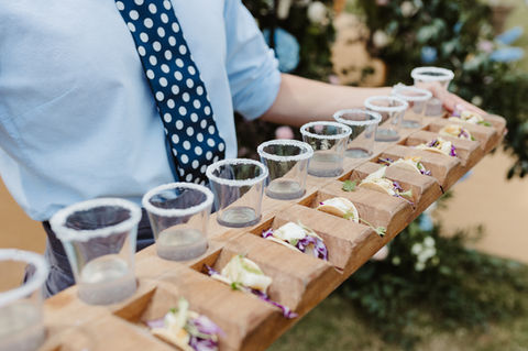 wedding canapes on a wooden board with a row of tequila shots