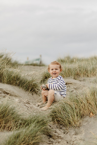 little boy sits in the sand dunes on west wittering beach