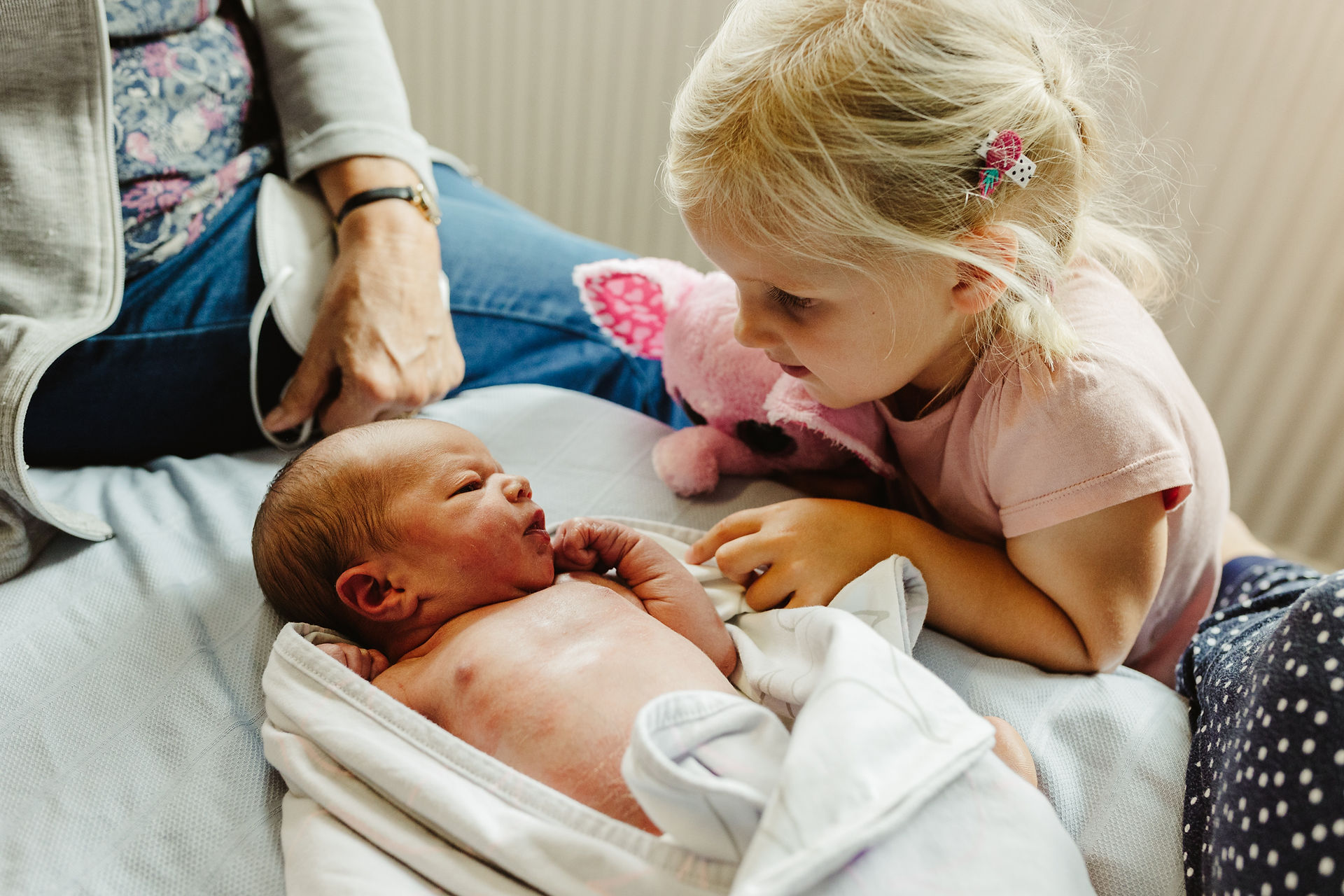 little blonde girls meets her baby sister for the first time