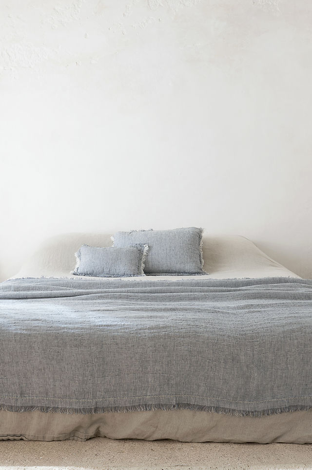 plaid bleu clair avec coussins assortis sur un lit