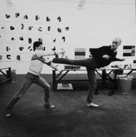 Emanuele Cacciatore holding steady while Sean Scully assaults his plate with a karate kick, cancelled. Photo: © 1987 Richard Tullis