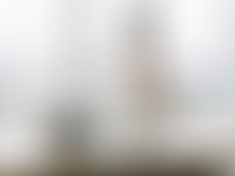 A business woman looks out her floor-to-ceiling office window at the city