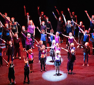 Large group of students performing a high-energy dance routine on stage during dance lessons at Vision Theatre Arts, Biggleswade