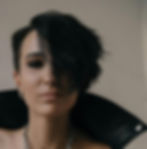 woman with short black hair with one side shaved and one side teased up wearing a black leather jacket with the collar flipped up