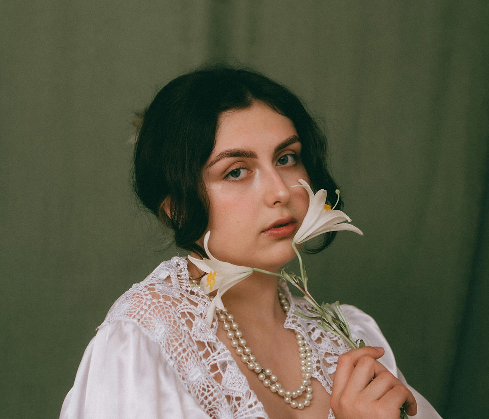 a woman in a white lace blouse holding a lily to her face