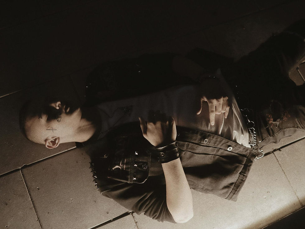 A man wearing a dark denim studded jacket and jeans lying on the floor