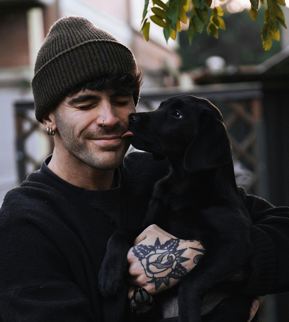 A man with tattoos and piercings holding a black dog